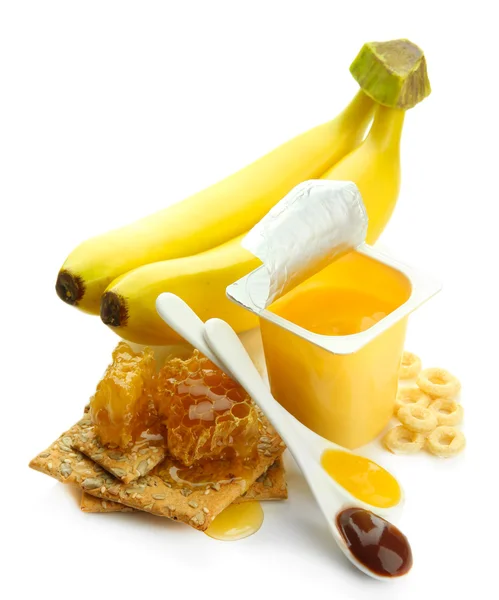 Dessert savoureux dans une tasse en plastique ouverte et peignes à miel, banane, isolé sur blanc — Photo