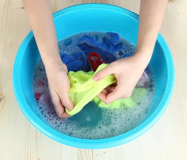 Hand washing in plastic bowl on wooden table close-up — Stock Photo, Image