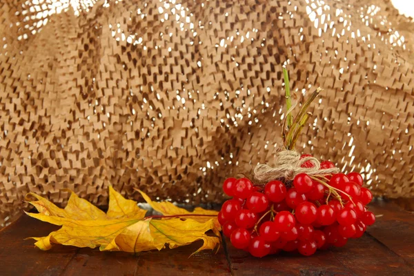 갈색 바탕에 테이블에 노란 잎가 막 살 나무속의 붉은 열매 — 스톡 사진
