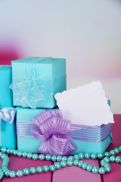 Cajas de regalo con etiqueta en blanco y chaplet en la mesa sobre fondo brillante — Foto de Stock