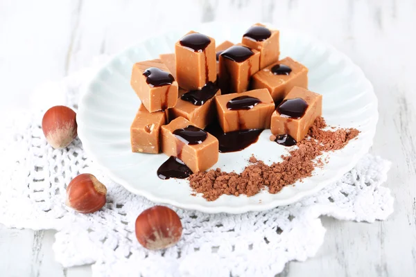 Many toffee on plate on napkin on wooden table — Stock Photo, Image