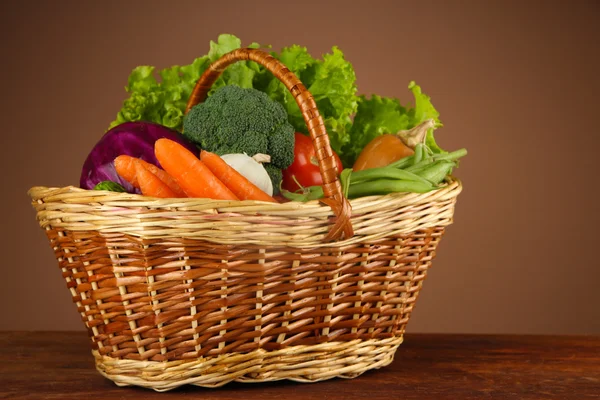 Verschillende groenten in mand op tafel op bruine achtergrond — Stockfoto