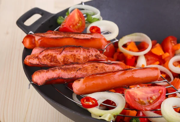 Salsichas deliciosas com legumes em wok na mesa de madeira close-up — Fotografia de Stock