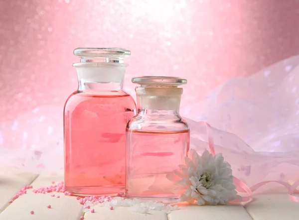 Bouteilles en verre avec essence de couleur, sur fond rose — Photo