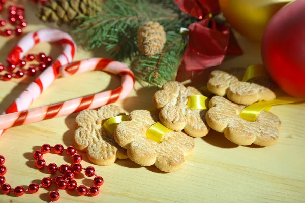 Cookies on ribbons with Christmas decorations on wooden table — Stock Photo, Image