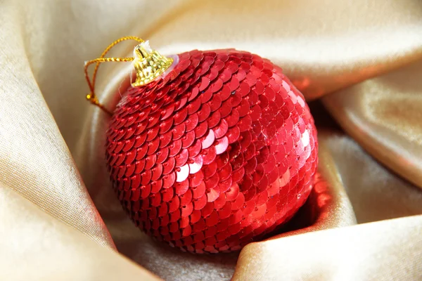 Hermosa bola de Navidad en tela de satén dorado — Foto de Stock