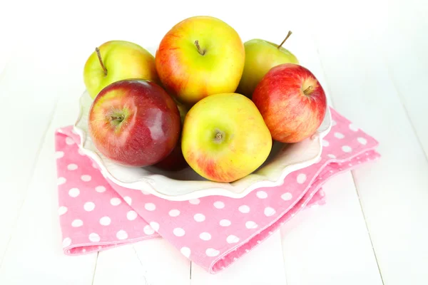 Saftiga äpplen på plattan på vita träbord — Stockfoto