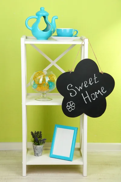 Composición de varios muebles para el hogar en estante blanco sobre fondo de pared verde — Foto de Stock