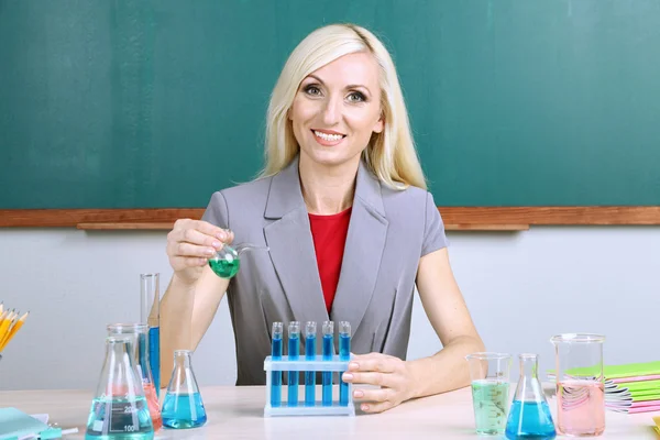 Chemistry teacher with tubes sitting at table — Stock Photo, Image