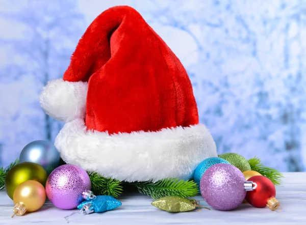 Komposition mit Weihnachtsmann rot Hut und Weihnachts-Dekorationen auf hellem Hintergrund — Stock fotografie