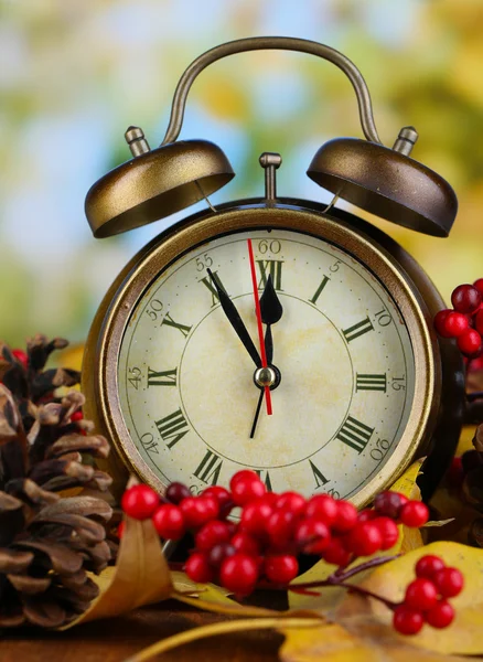 Alte Uhr auf Herbstblättern auf Holztisch vor natürlichem Hintergrund — Stockfoto