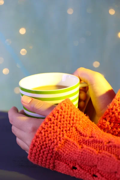 Hands holding mug of hot drink, close-up, on bright background — Stock Photo, Image