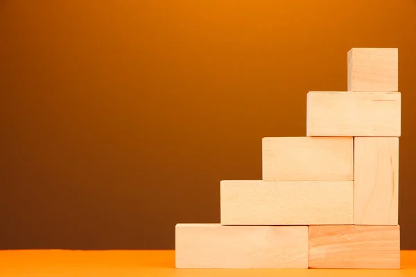 Bloques de juguete de madera en la mesa sobre fondo amarillo — Foto de Stock