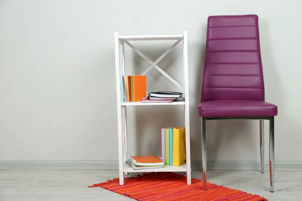 Gyönyörű belső a modern színű szék, fa állványon, falon háttér könyvek — Stock Fotó