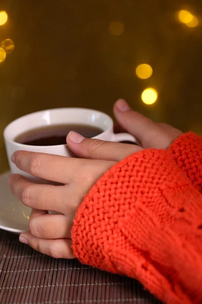 Hands holding mug of hot drink, close-up, on bright background — Stock Photo, Image