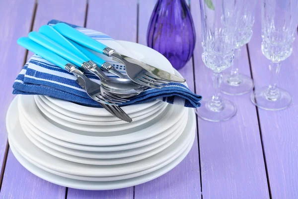 Clean dishes on wooden table on color background — Stock Photo, Image