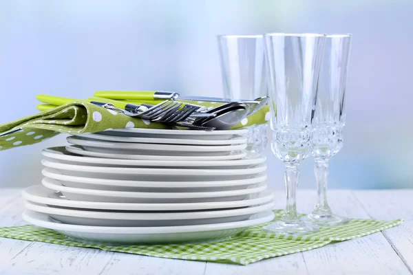 Sauberes Geschirr auf Holztisch auf hellem Hintergrund — Stockfoto