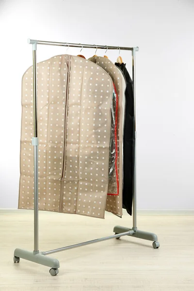 Kleidung in Etuis zur Aufbewahrung auf Kleiderbügeln, auf grauem Hintergrund — Stockfoto