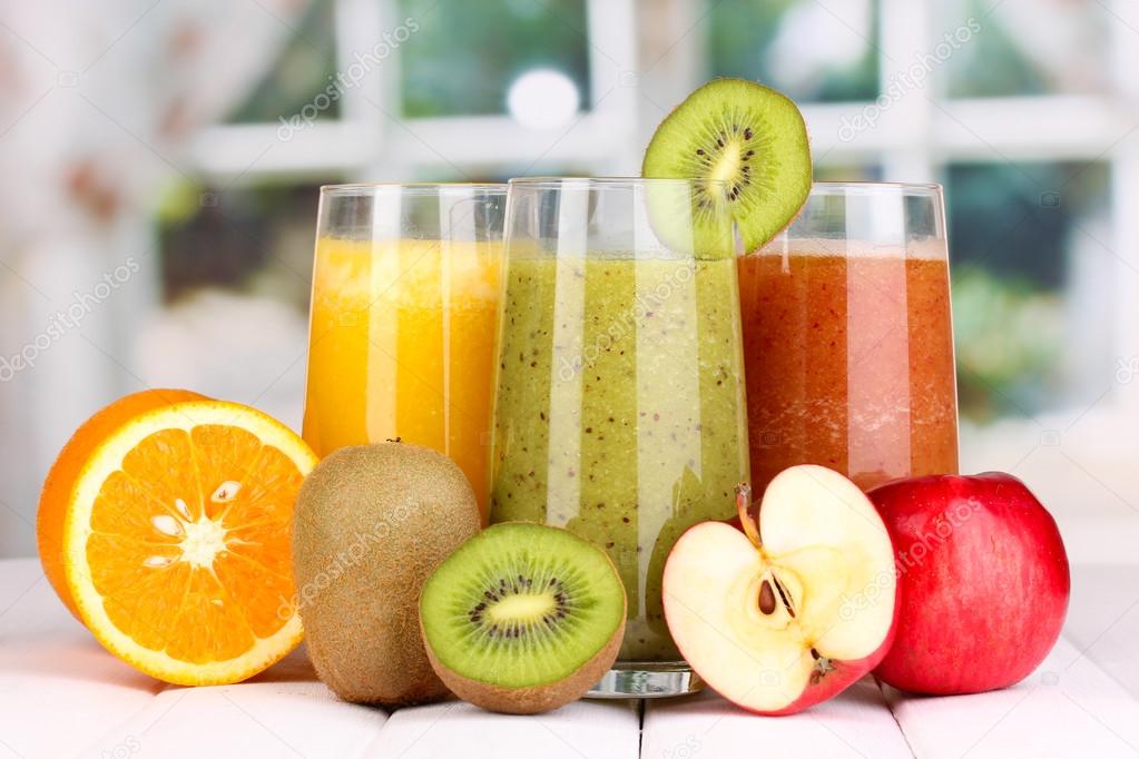 fresh fruit juices on wooden table, on window background