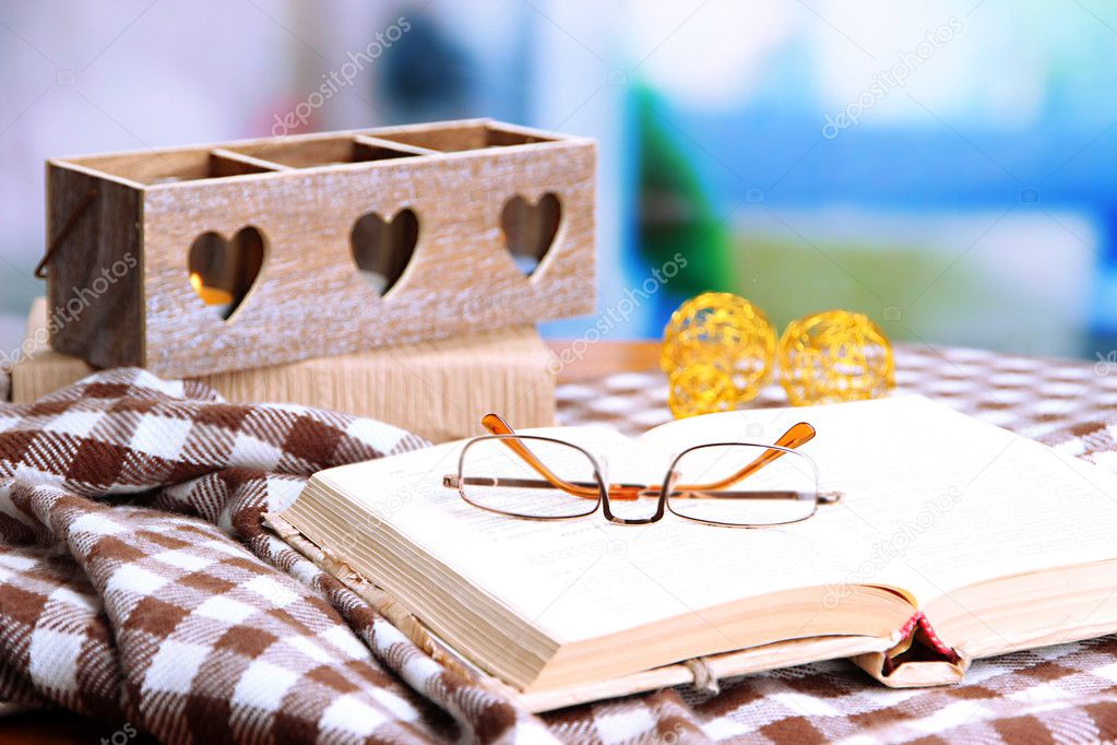 Composition with old book, eye glasses, candles, and plaid on bright background