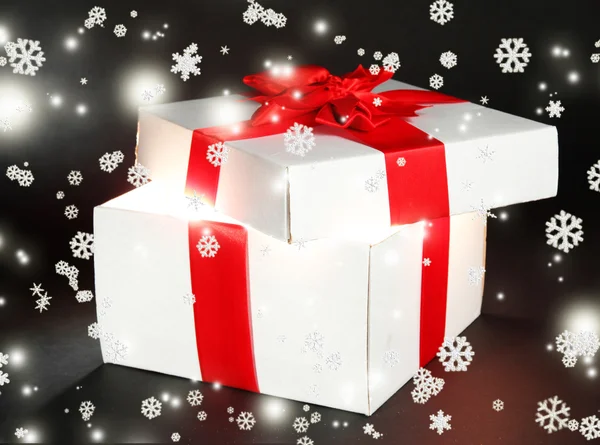 Gift box with bright light on it on dark grey background — Stock Photo, Image