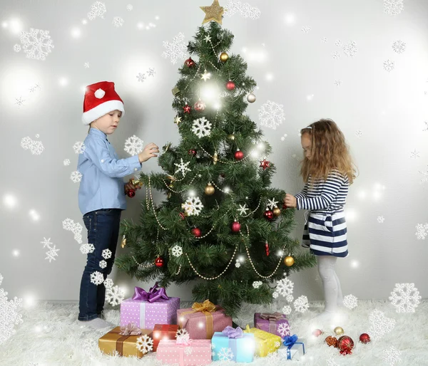 Kids decorating Christmas tree with baubles in room — Stock Photo