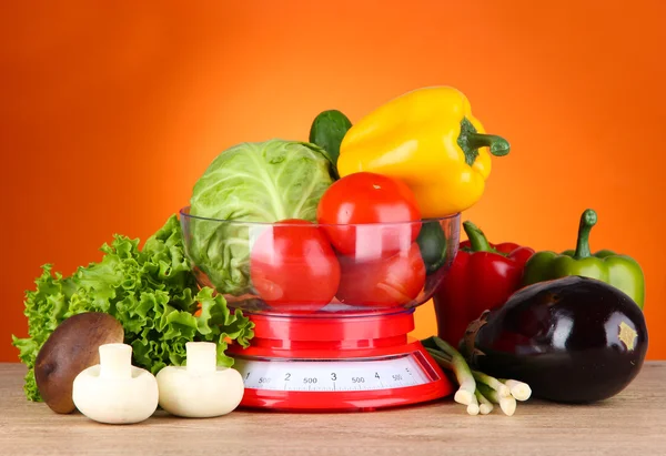 Verse groenten in schalen op tafel op oranje achtergrond — Stockfoto