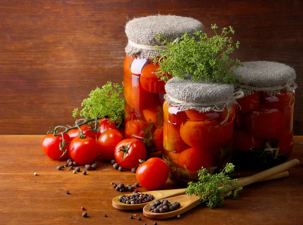 Tasty canned and fresh tomatoes on wooden table — Stock Photo, Image