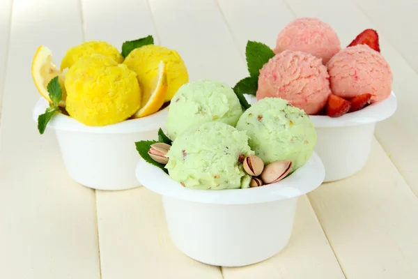 Tasty ice cream scoops in bowls, on wooden table — Stock Photo, Image