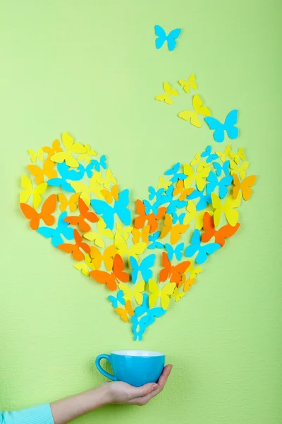 Mariposas de papel vuelan fuera de la taza sobre fondo de pared verde —  Fotos de Stock