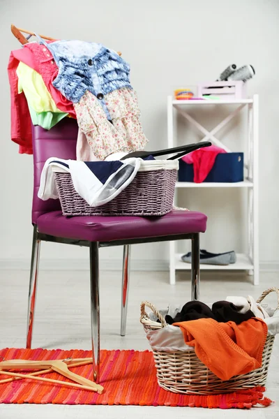 Kleiderhaufen auf farbigem Stuhl, auf grauem Hintergrund — Stockfoto