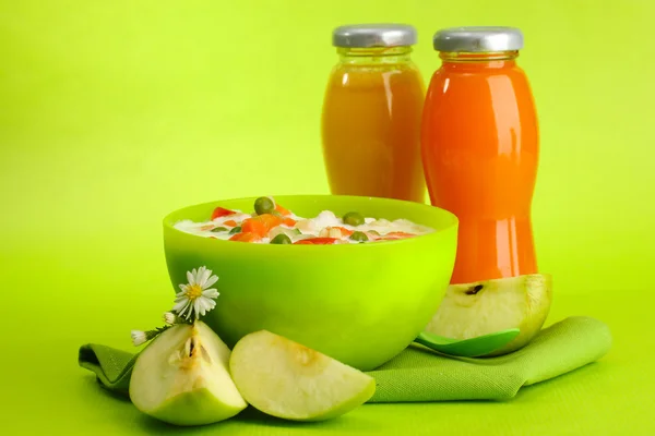 Sabrosos alimentos dietéticos y botellas de jugo, sobre fondo verde —  Fotos de Stock