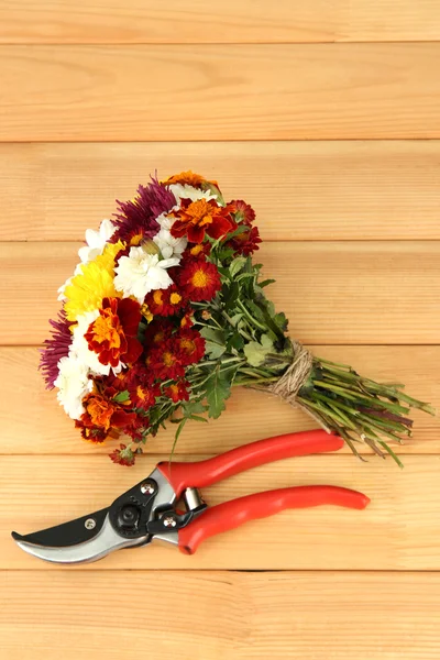 Zahradnické nůžky s květinami na dřevěné pozadí — Stock fotografie