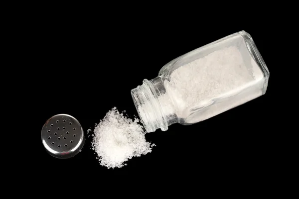 Salt shaker with spilled salt isolated on black — Stock Photo, Image