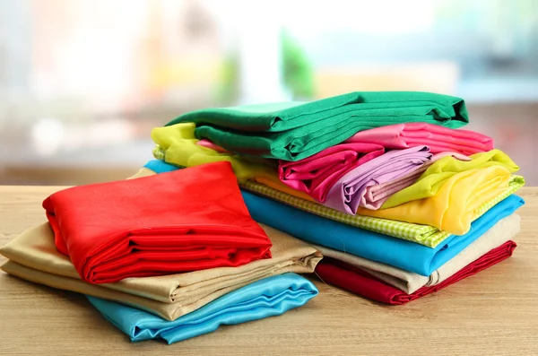 Heap of cloth fabrics on wooden table — Stock Photo, Image