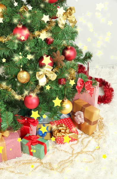 Dekorerad julgran med gåvor på grå vägg bakgrund — Stockfoto