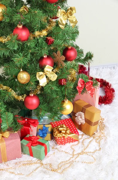 Zdobené vánoční stromeček s dárky na šedou stěnu pozadí — Stock fotografie