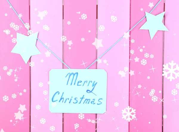 Bord met woorden vrolijk kerstfeest op roze houten tafel achtergrond close-up — Stockfoto