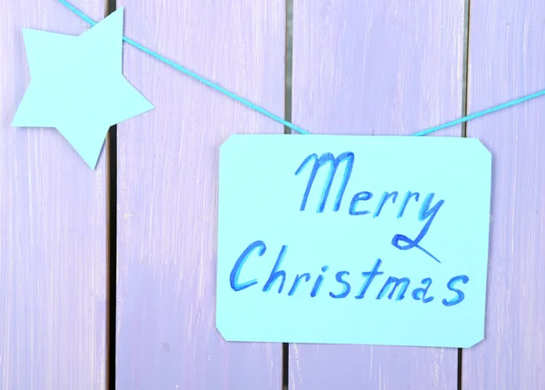 Schild mit den Worten Frohe Weihnachten auf lila Holztischhintergrund Nahaufnahme — Stockfoto