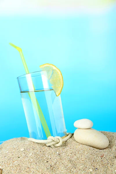 Beach cocktail in sand on blue background — Stock Photo, Image