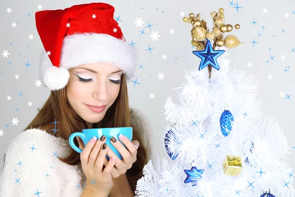 Hermosa chica sonriente cerca del árbol de Navidad con taza — Foto de Stock