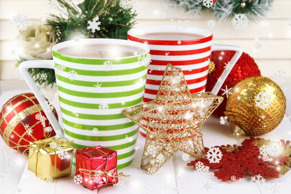 Cups of hot cacao with Christmas decorations on table on wooden background