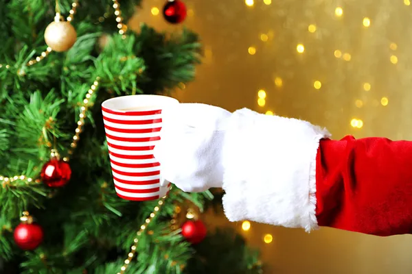 Santa holding mug in his hand, on bright background — Stock Photo, Image