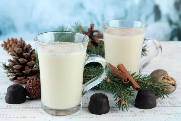 Cup of eggnog with fir branches and candies on table on bright background — Stock Photo, Image