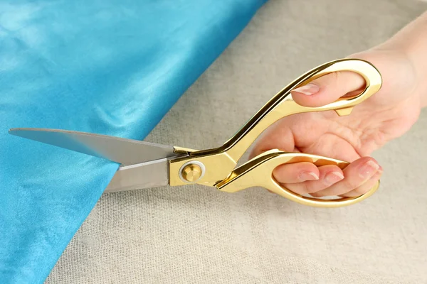 Seamstress cut blue fabric on beige fabric background — Stock Photo, Image