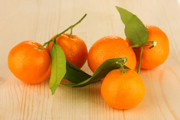 Tangerinas doces com folhas, em fundo de madeira — Fotografia de Stock