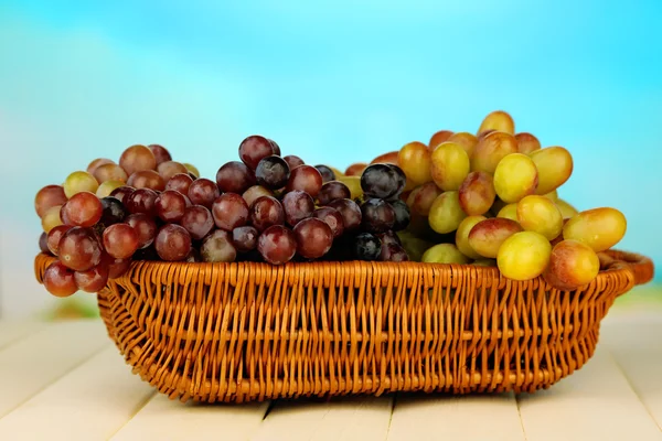 Uva fresca em esteira de vime em fundo brilhante — Fotografia de Stock