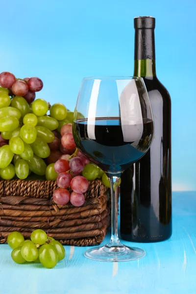 Mogna gröna och lila druvor i korg med vin på träbord på naturliga bakgrund — Stockfoto