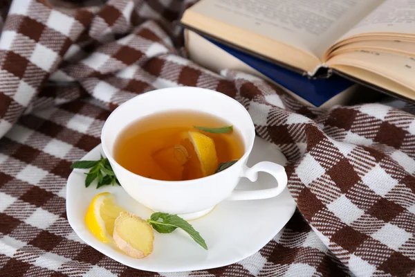 Tasse de thé au gingembre sur carreaux avec un livre — Photo