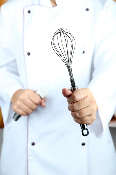 Corola y cuchillo en manos de cocinero sobre fondo brillante — Foto de Stock